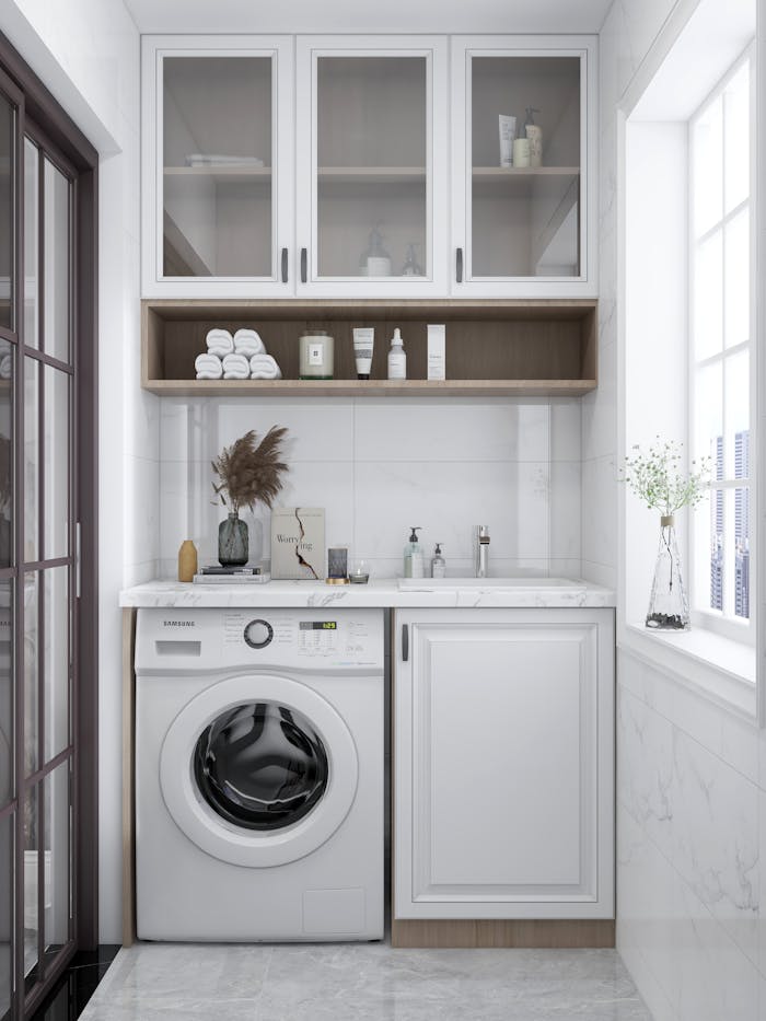 services-01 A sleek and bright laundry room featuring a washing machine, cabinets, and natural decor.